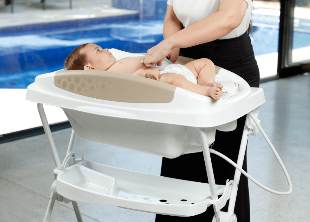 Mulher trocando a fralda do seu filho em uma banheira de bebê as melhores opções do mercado