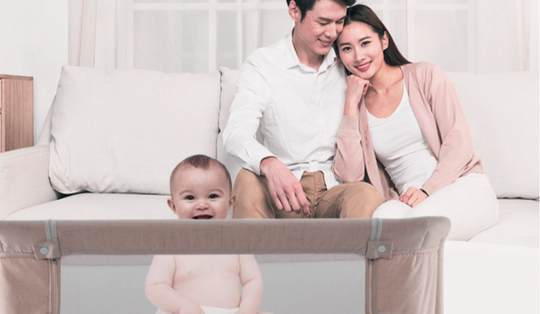 bebê em berço portátil ao lado dos pais com