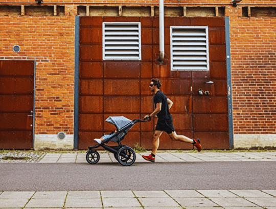 Homem correndo com um bebê no carrinho de bebê para corrida Thule Urban Glide 2 Jet gray