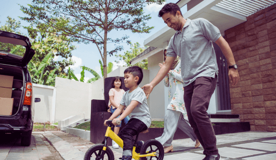 Pai ensinando seu filho a andar de bicicleta de equilíbrio infantil em um pátio ao ar livre