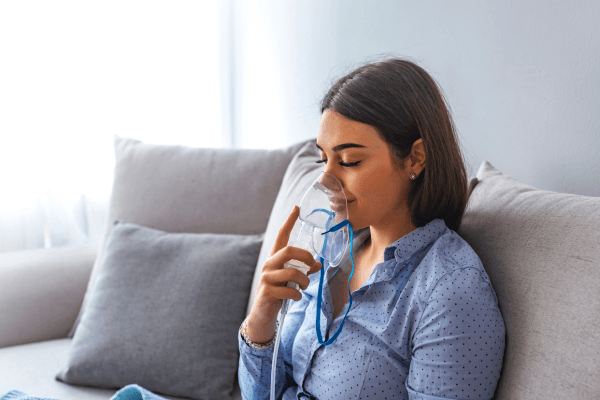 mulher adulta usando um inalador portátil