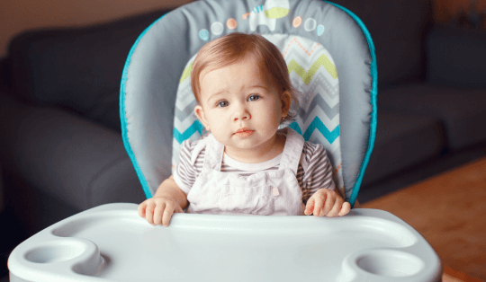 menina bebê sentada em uma cadeira de refeição com encosto azul celeste