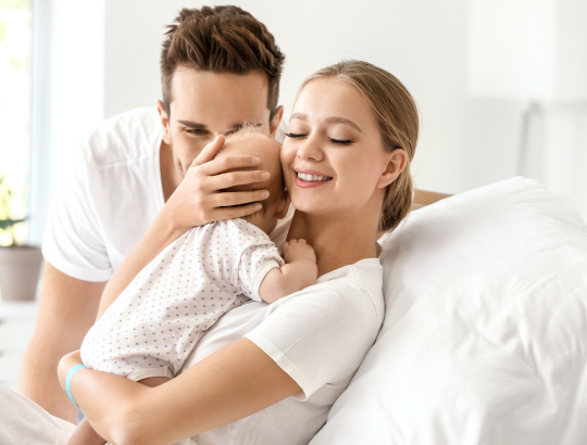 pais abraçando bebê usando uma roupinha saída maternidade bebê