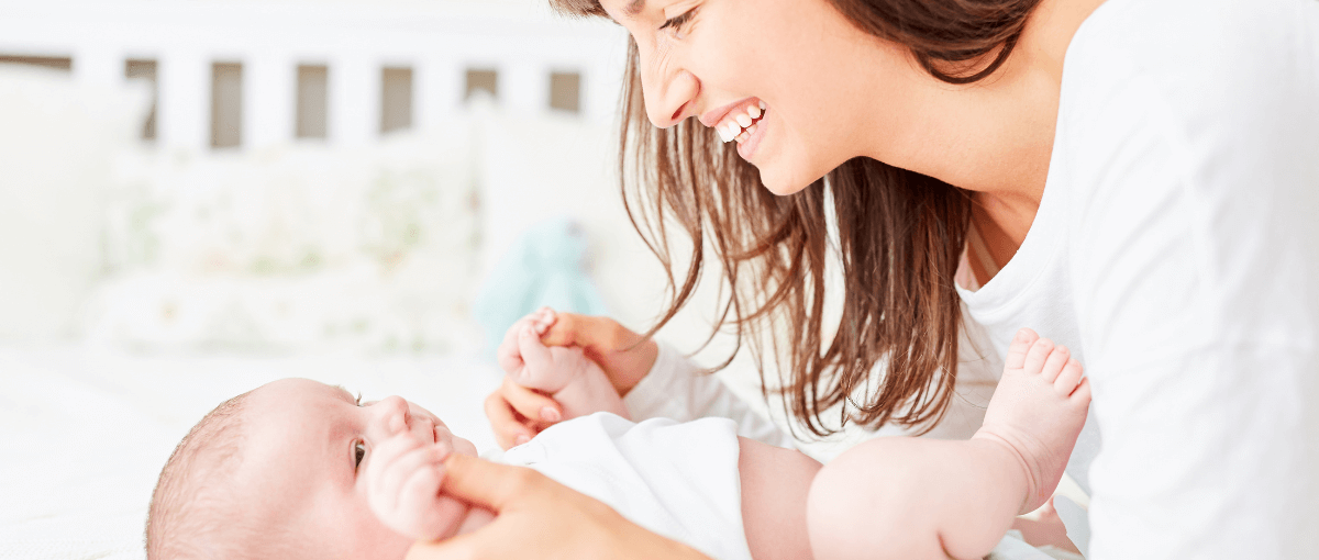 mãe sorrindo após a troca de fraldas em seu lindo bebê