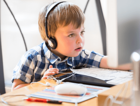 menino estudando enquanto usa um dos melhores abafadores de ruído para autismo