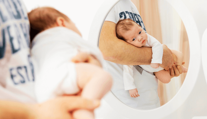 pai colocando o neném na posição vertical para aliviar as cólicas no bebê