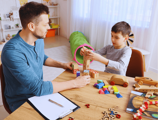 Pai brincando com um menino com transtorno do espectro autista com blocos de montar montessori